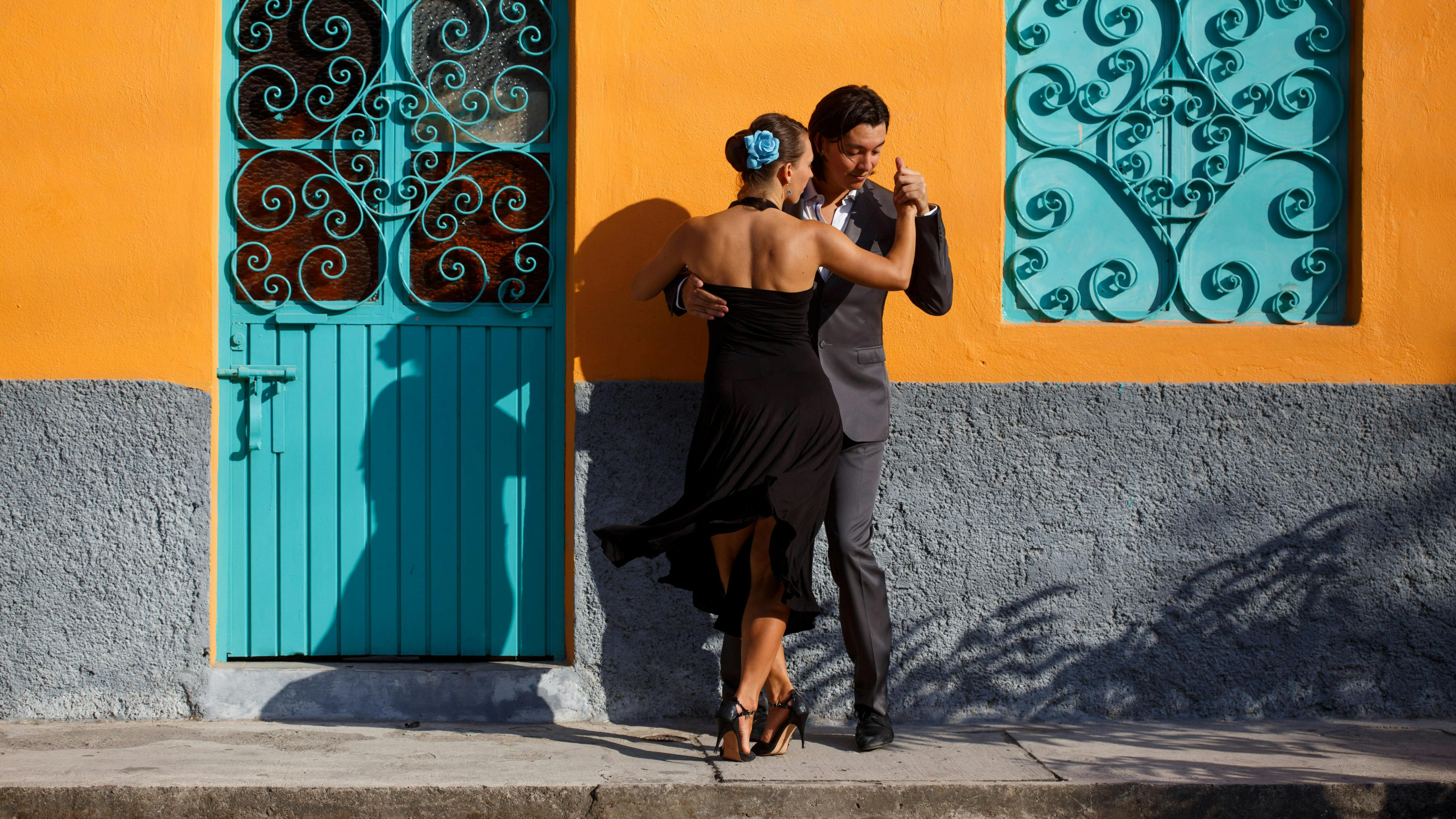 One-on-one bachata lesson in a small Latin dance studio, with the instructor and student reflected in mirrors